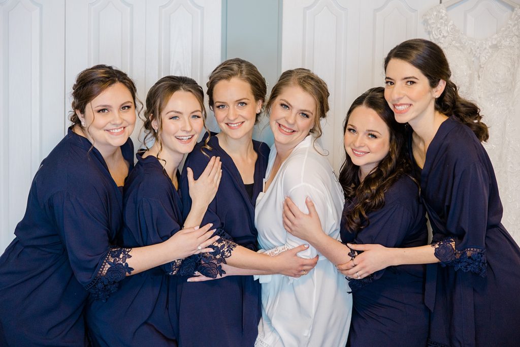 bride with bridal party in matchng getting ready robes for temples country winter wedding photographed by Brittany Navin Photography