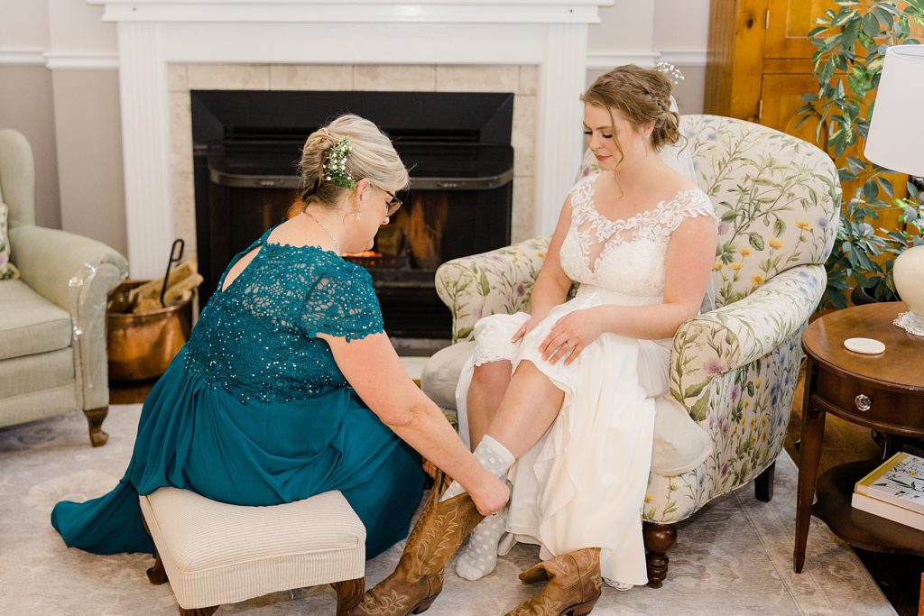 mother of bride helping bride put her cowgirl boots on for temples country winter wedding photographed by Brittany Navin Photography