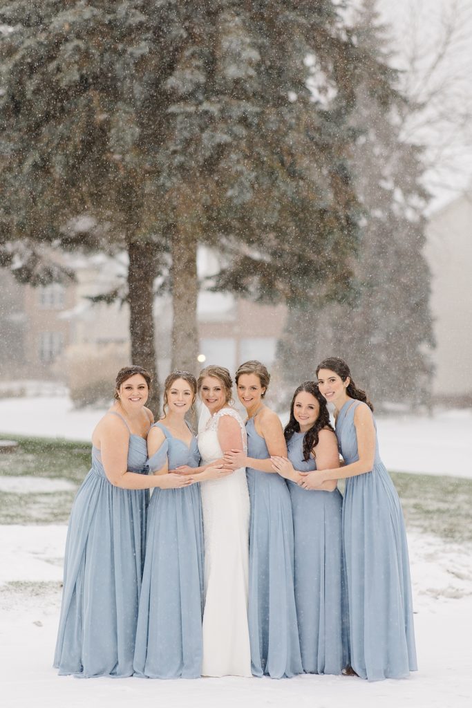 bride with bridesmaids wearing dusty blue bridesmaid dresses from azazie for temples country winter wedding photographed by Brittany Navin Photography