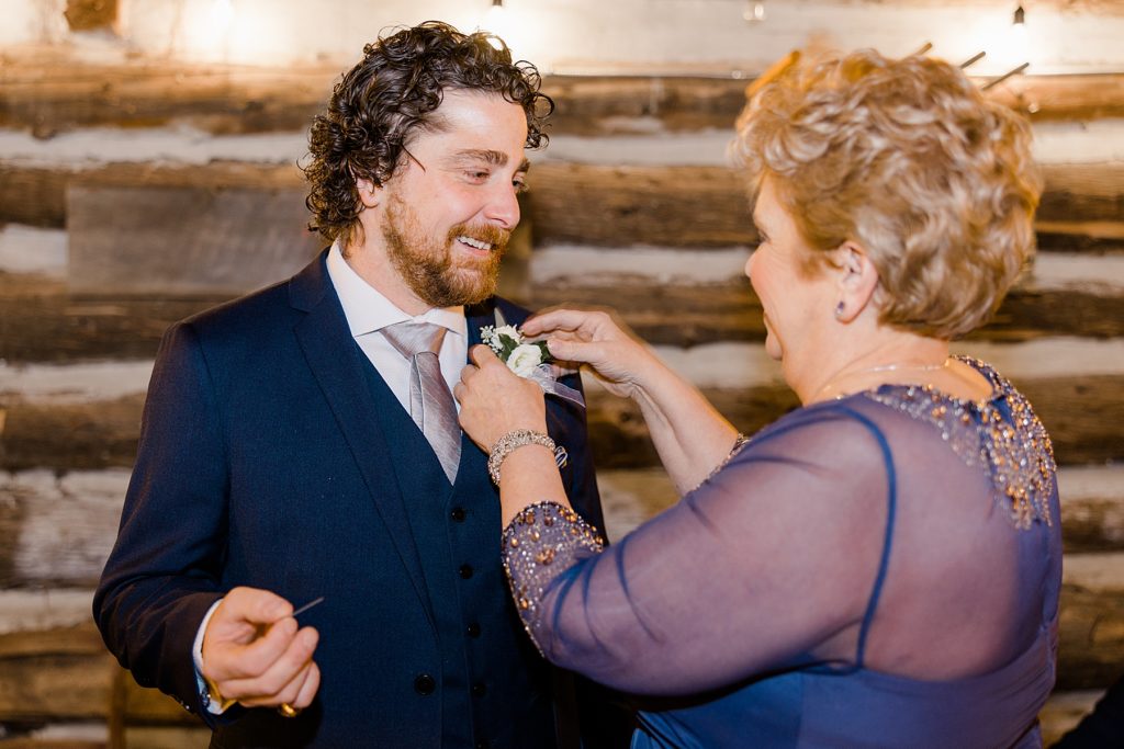 grooms mom is putting on grooms boutonniere for temples country winter wedding photographed by Brittany Navin Photography
