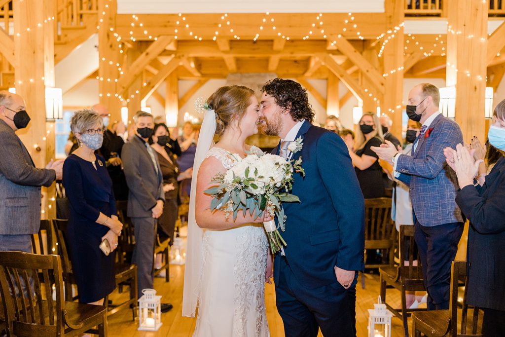 bride and groom kiss half way down the aisle temples country winter wedding photographed by Brittany Navin Photography