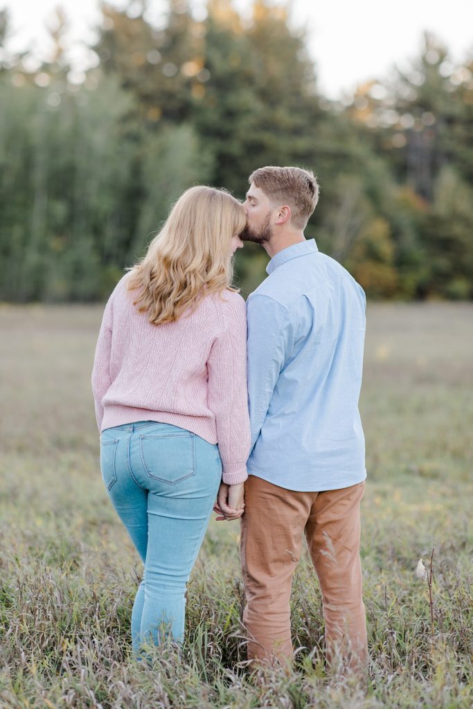 couple facing away from the camera as he gives her a kiss on the forehead at Arnprior engagement session at Gillies Grove photographed by Brittany Navin Photography