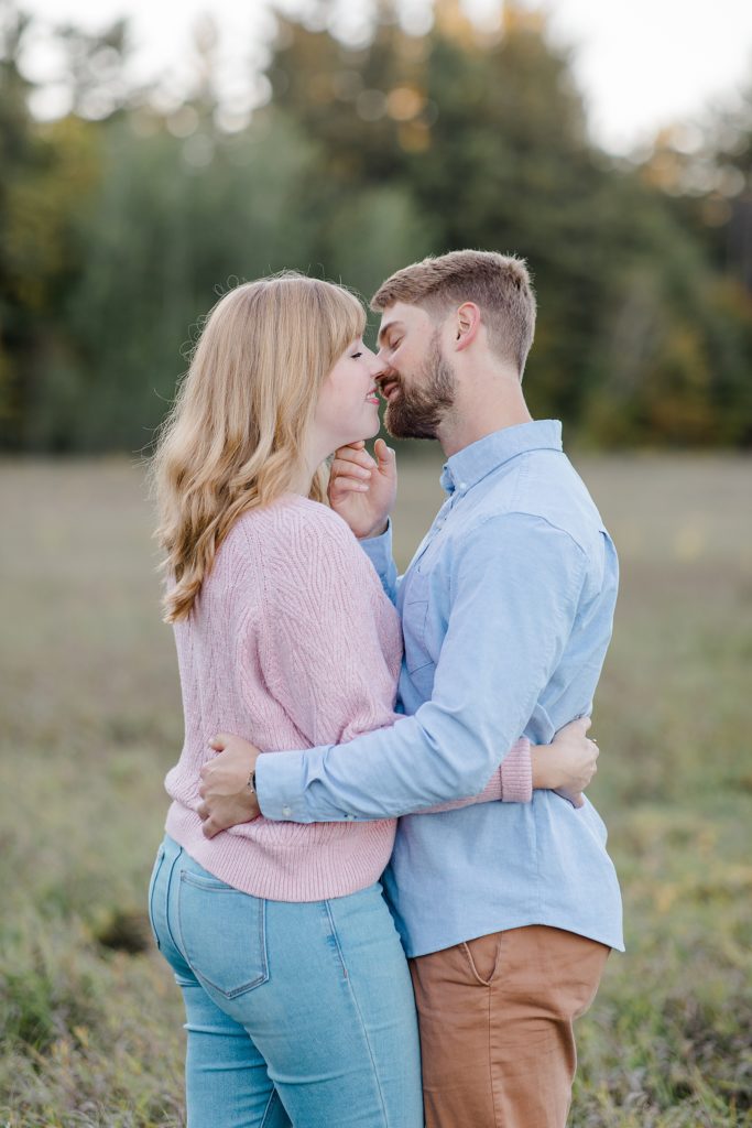 he is pulling his fiance in for a kiss at Arnprior engagement session at Gillies Grove photographed by Brittany Navin Photography