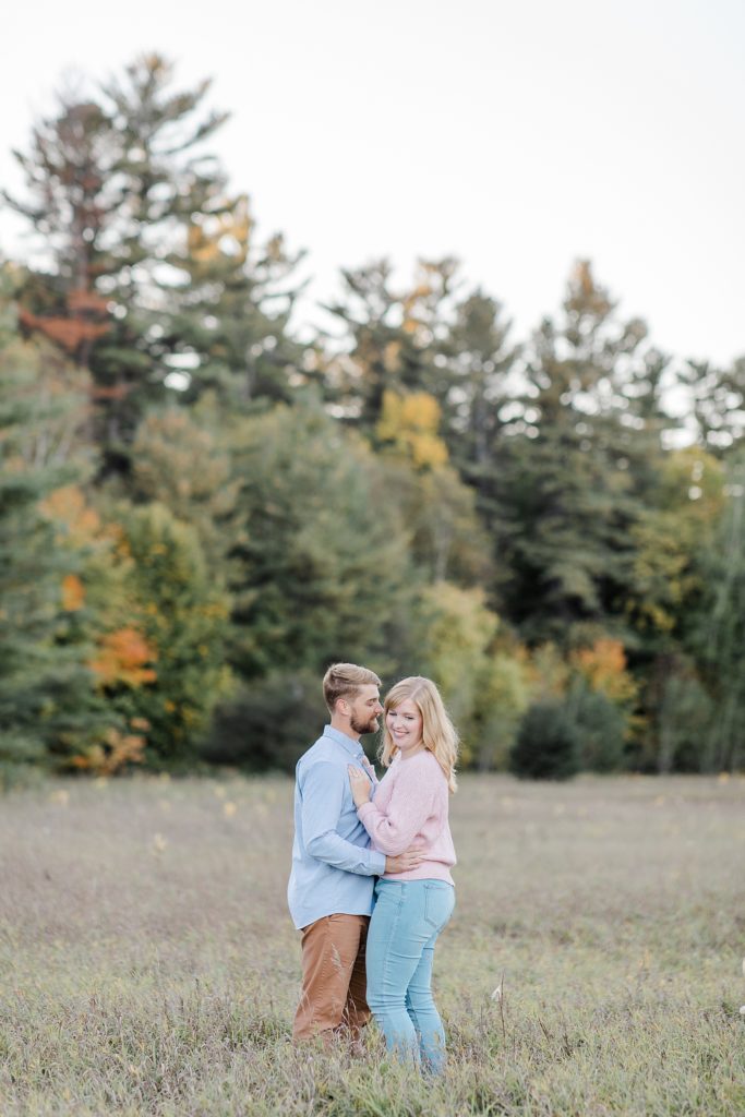 couple standing in long wispy grass together at Arnprior engagement session at Gillies Grove photographed by Brittany Navin Photography