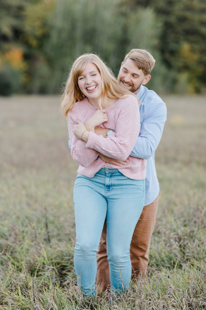 he sneak attacked his fiance from behind and gave her a huge hug at Arnprior engagement session at Gillies Grove photographed by Brittany Navin Photography