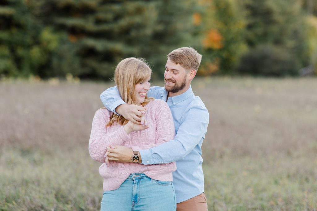 he has his fiance all wrapped up in his ar,s at Arnprior engagement session at Gillies Grove photographed by Brittany Navin Photography