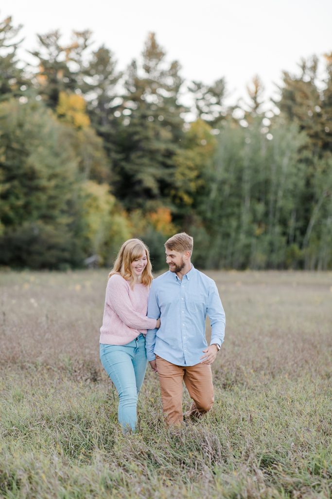 couple walking through long grass field at Arnprior engagement session at Gillies Grove photographed by Brittany Navin Photography