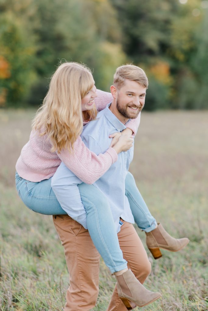 he is giving his fiance a piggy back ride at Arnprior engagement session at Gillies Grove photographed by Brittany Navin Photography