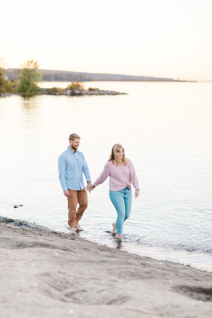 couple walking ankle deep in water at Arnprior engagement session at Robert Simpson Park photographed by Brittany Navin Photography