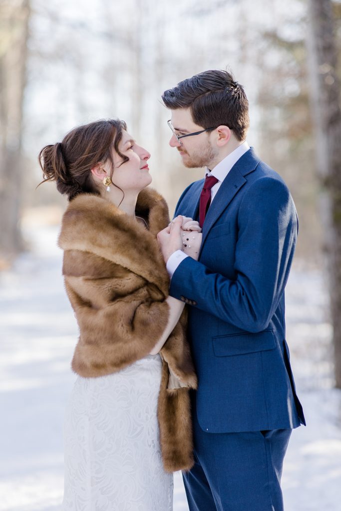bride and groom keeping each others hands warm during portraits at Beckwith winter elopement photographed by Brittany Navin Photography 