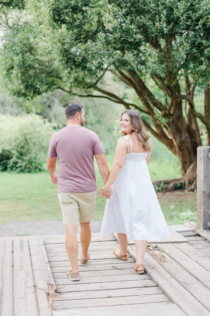 couple walking across bridge at dominion arboretum engagement session phtoographed by Brittany Navin Photography