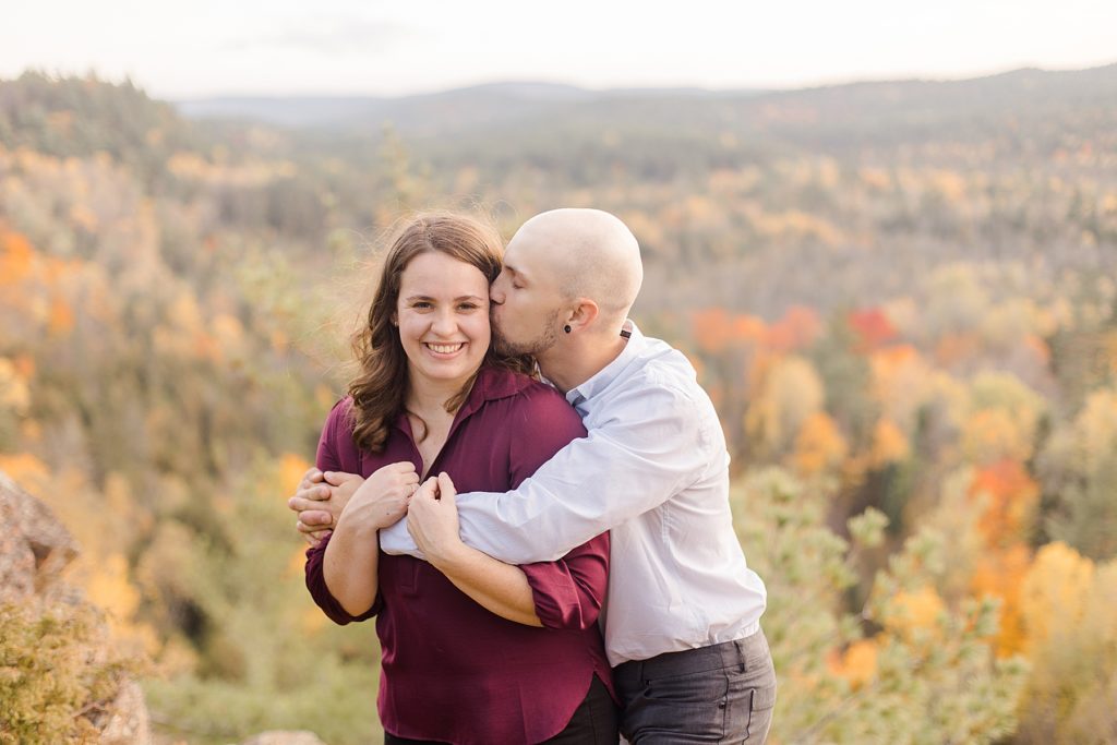 he is giving her cheek kisses at eagle's nest fall engagement photographed by Brittany Navin Photography