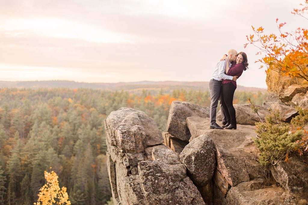 couple hugging on cliff at eagle's nest fall engagement photographed by Brittany Navin Photography