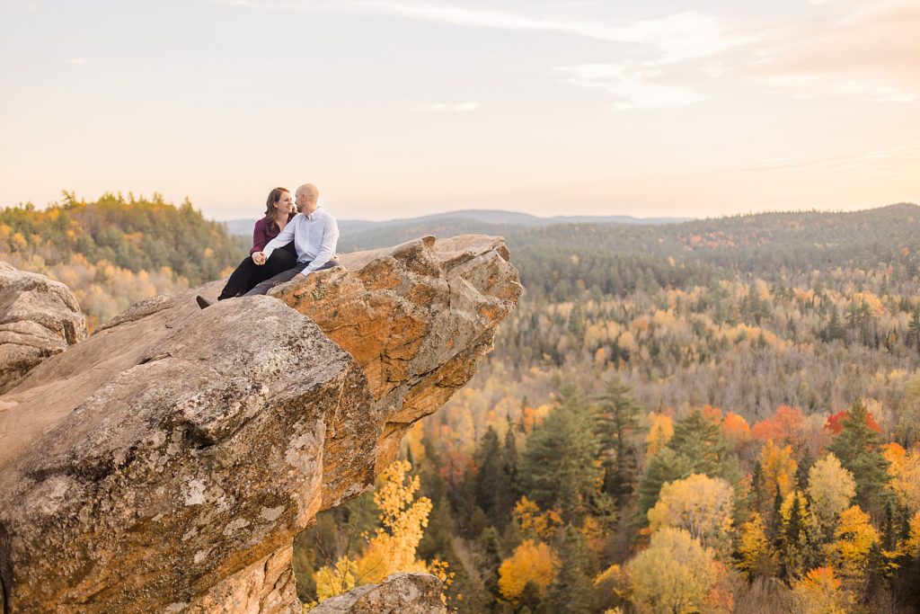 couple sitting at top of cliff at eagle's nest fall engagement photographed by Brittany Navin Photography