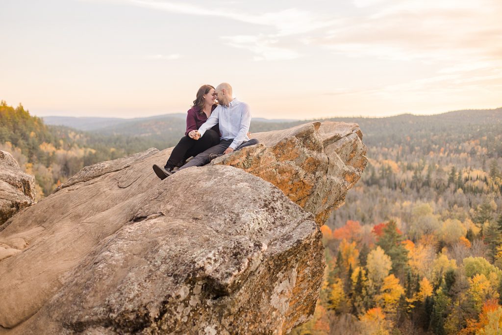 couple sitting together at top of cliff at eagle's nest fall engagement photographed by Brittany Navin Photography
