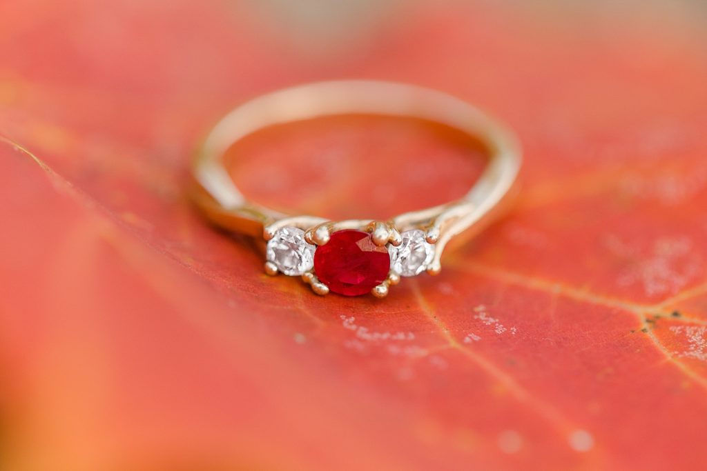 close up of engagement ring on top of red maple leaf photographed by Brittany Navin Photography