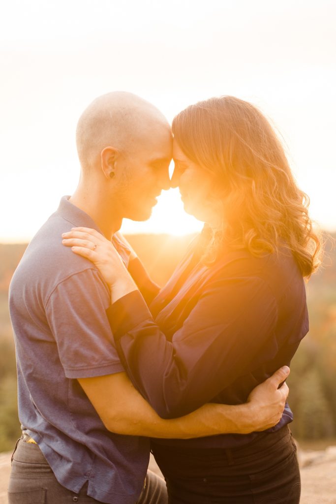 coupe forehead to forehead as the sun shines through between them at eagle's nest fall engagement photographed by Brittany Navin Photography