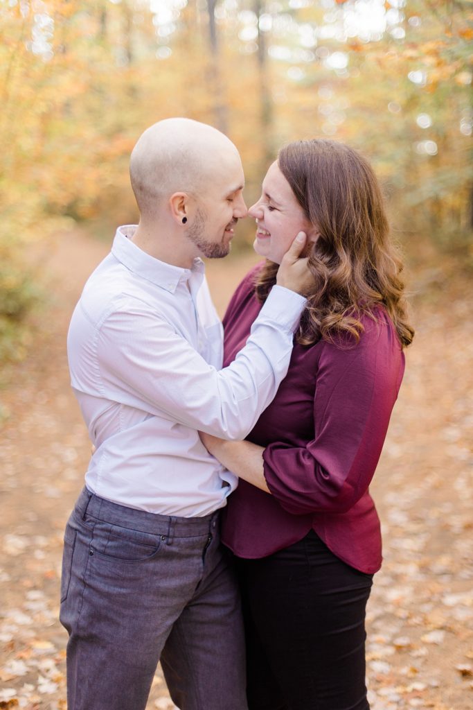 couple about to kiss while on a trail filled with autumn leaves at eagle's nest fall engagement photographed by Brittany Navin Photography
