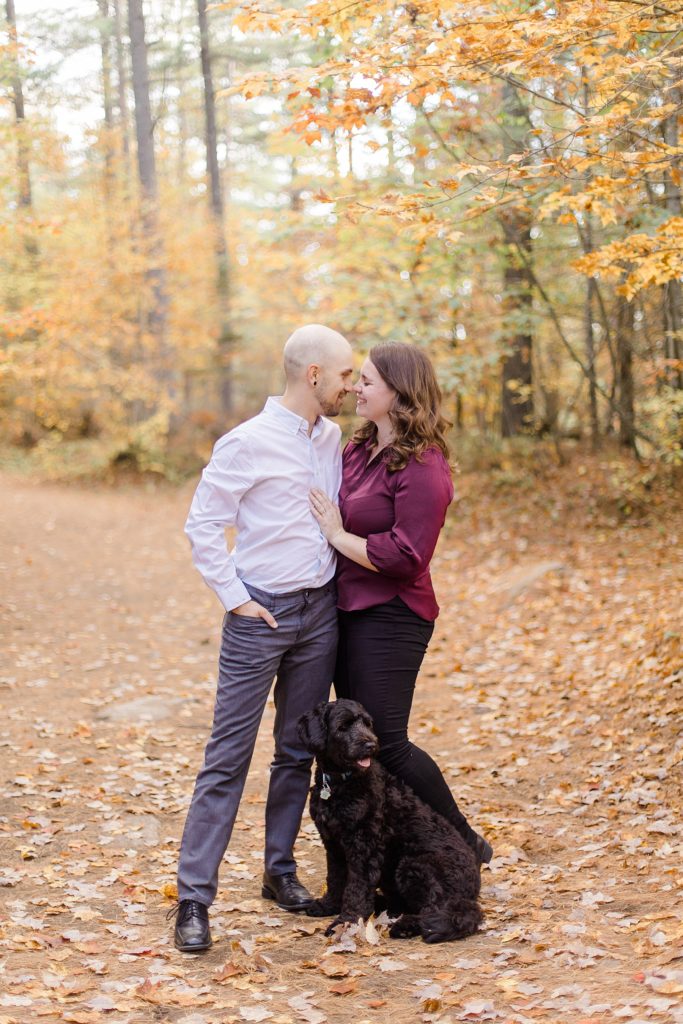 couple in a trail with autumn leaves and their puppy at eagle's nest fall engagement photographed by Brittany Navin Photography