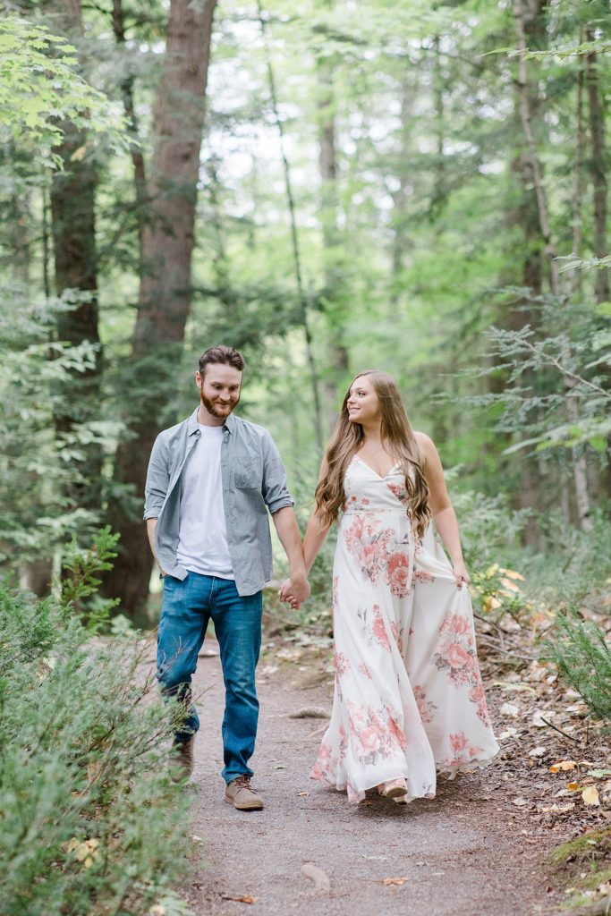 couple is walking through trail together at mill of kintail engagement session photographed by Brittany Navin Photography