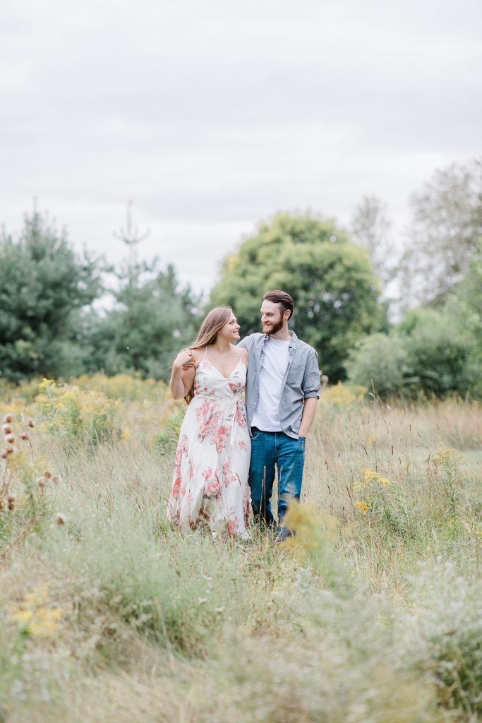 couple walking through long wispy grass at mill of kintail engagement session photographed by Brittany Navin Photography