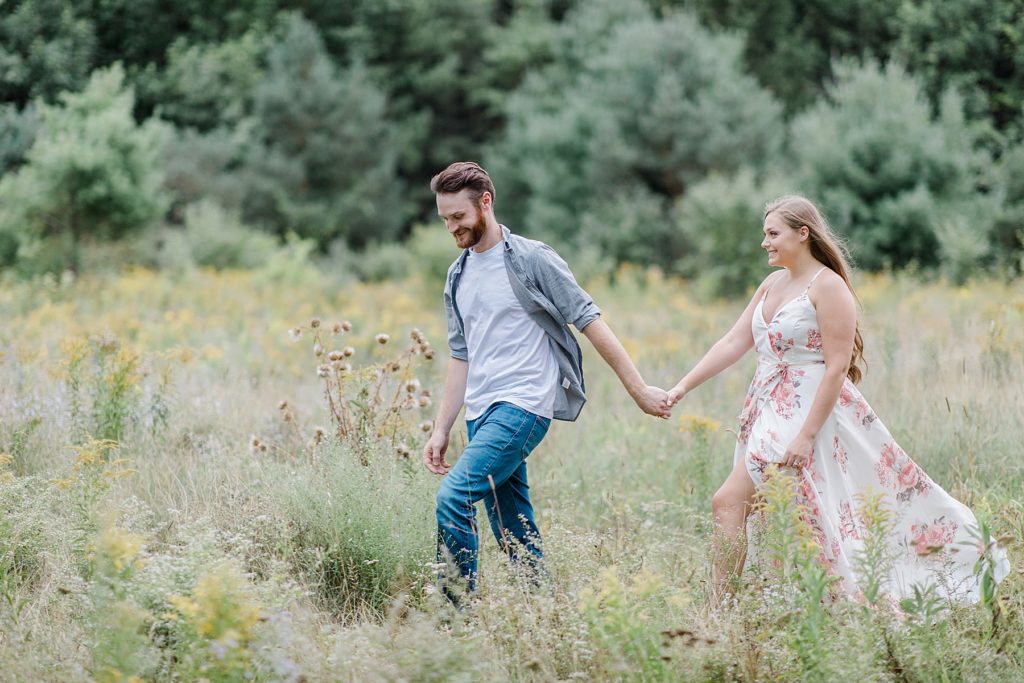 couple walking through long grass in wide open field at mill of kintail engagement session photographed by Brittany Navin Photography