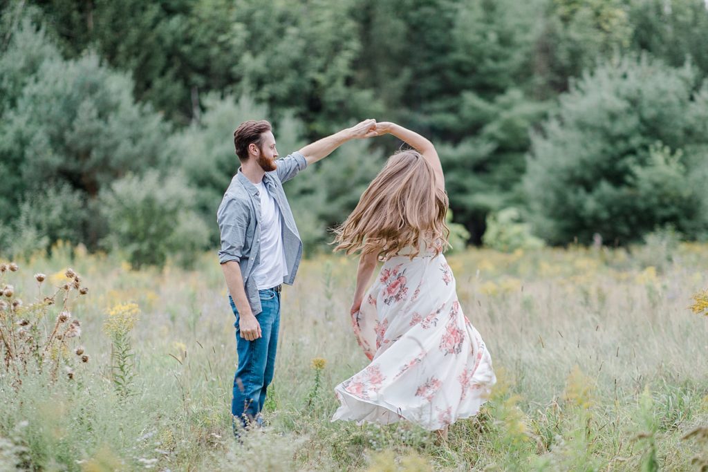 couple dancing together in a field of long wispy grass at mill of kintail engagement session photographed by Brittany Navin Photography
