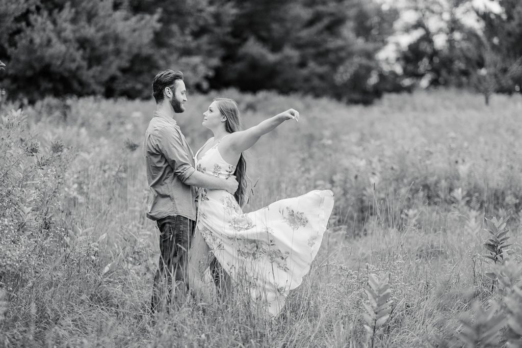 couple standing together while she throws the flowy part of her dress in the air at mill of kintail engagement session photographed by Brittany Navin Photography