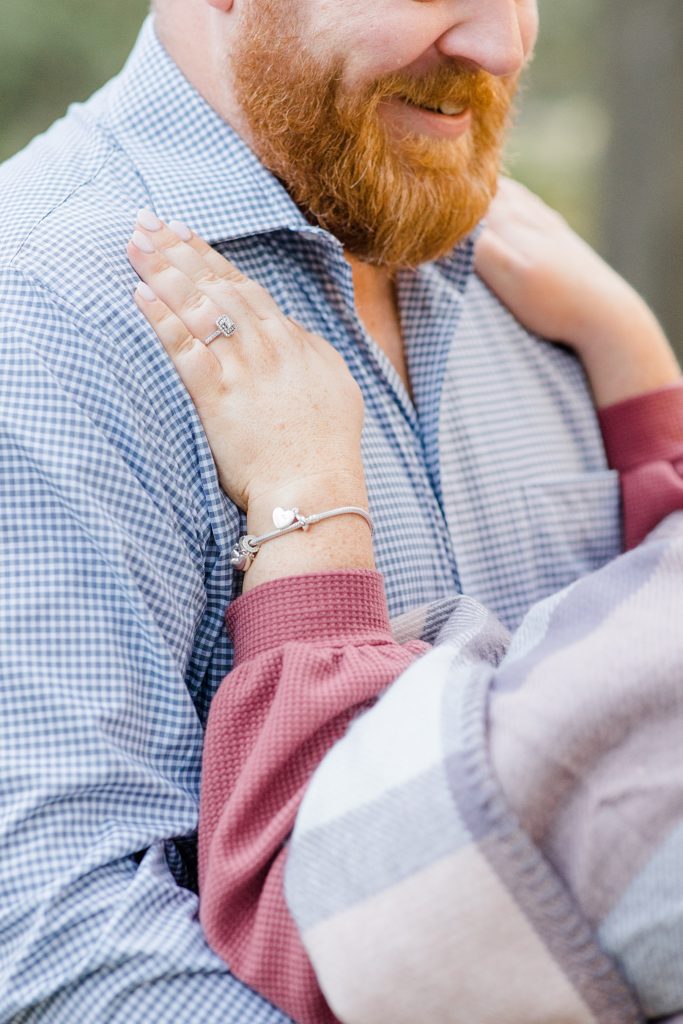 close up of her hands on his chest showcasing the engagement ring
