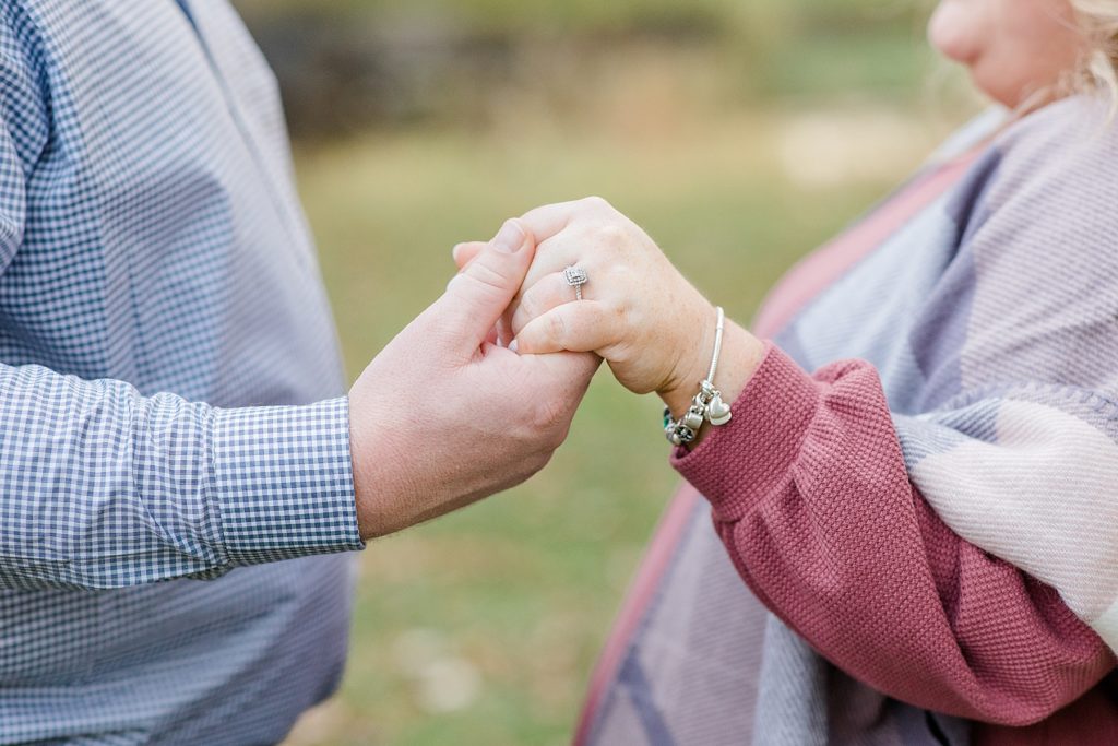 close up of couple holding hands showcasing her engagement ring At Stewart Park Engagement photographed by Brittany Navin Photography