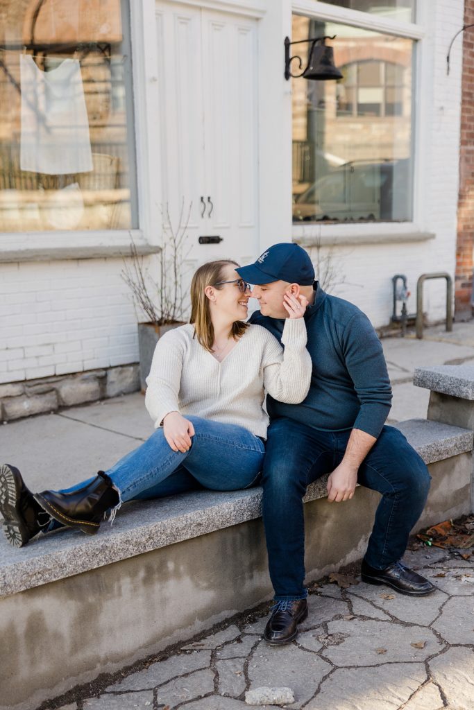 couple sitting outside of tin barn market at Downtown Almonte Engagement Session photographed by Brittany Navin Photography