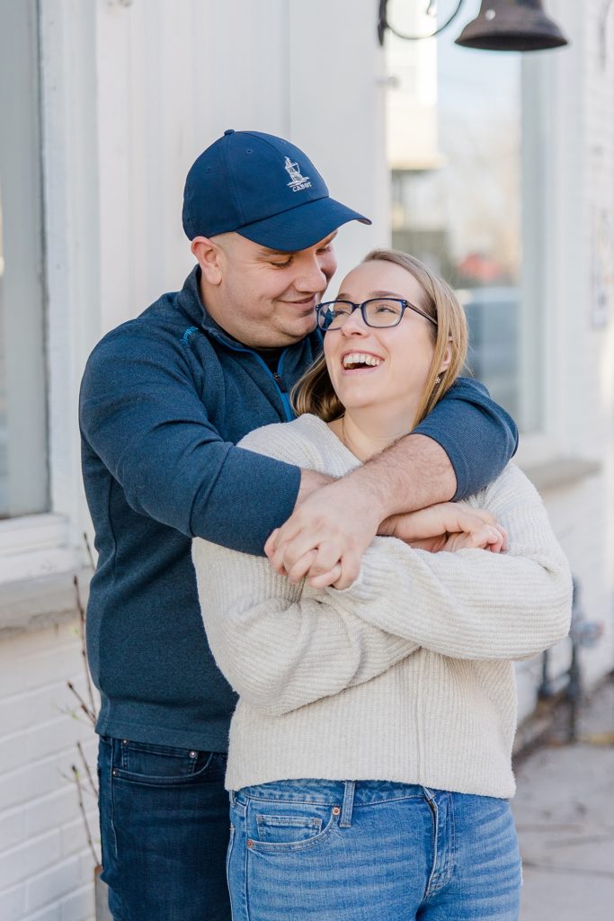 couple laughing as he has her wrapped up in his arms at Downtown Almonte Engagement Session photographed by Brittany Navin Photography
