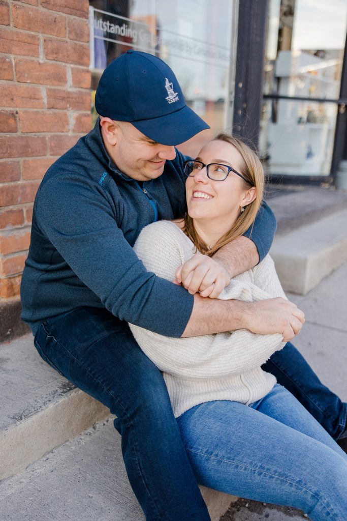 couple cuddled up on a step at Downtown Almonte Engagement Session photographed by Brittany Navin Photography