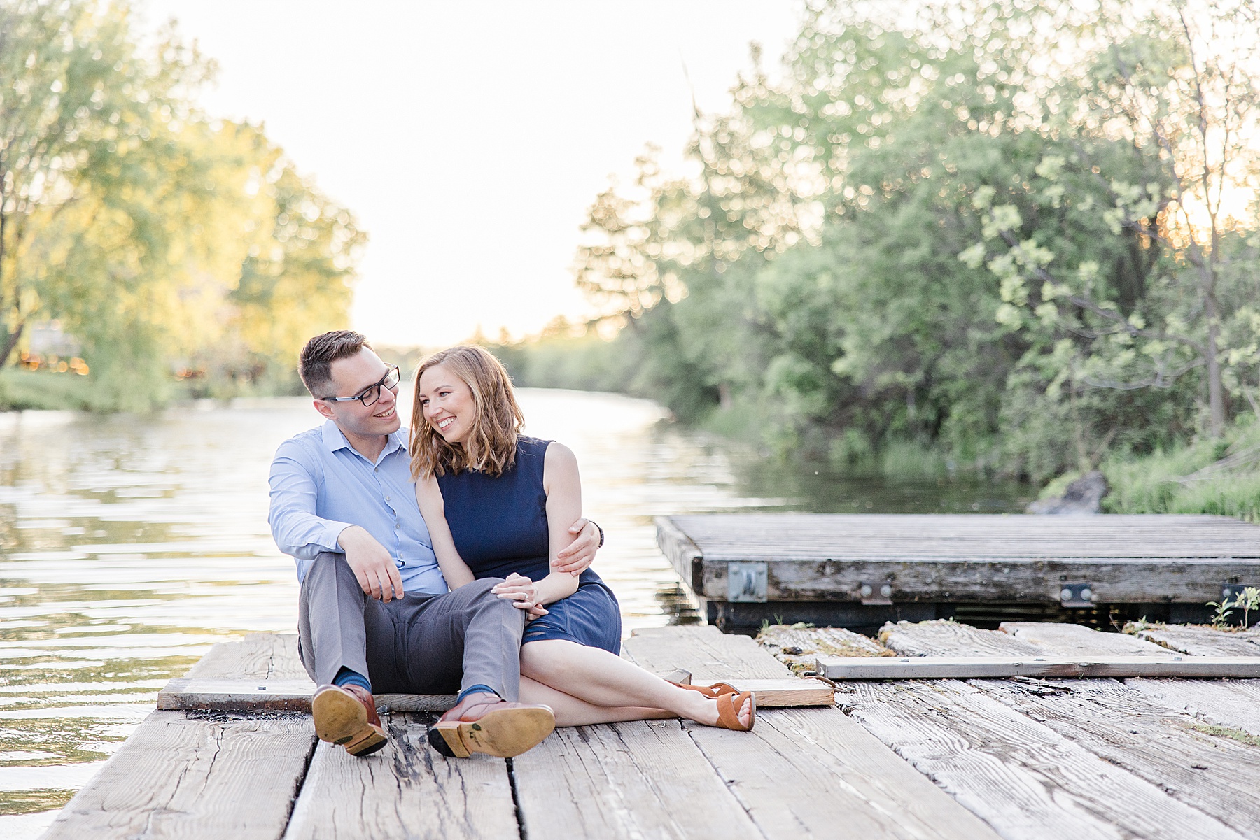 couple sitting on the dock together and laughing at Merrickville Locks Engagement Session Photographed by Brittany Navin Photography