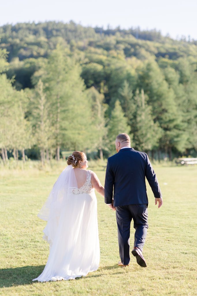 bride and groom walking for photos  at calabogie peaks summer wedding photographed by Brittany Navin Photography
