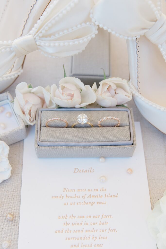 Detail image of wedding invitation paired with bella belle bridal shoes and three bridal rings showcased in a rectangular ring box photographed by Brittany Navin Photography