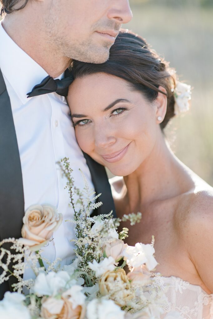 close up portrait of bride leaning against her grooms chest at the coastal opulence beach wedding editorial photographed by Brittany Navin Photography