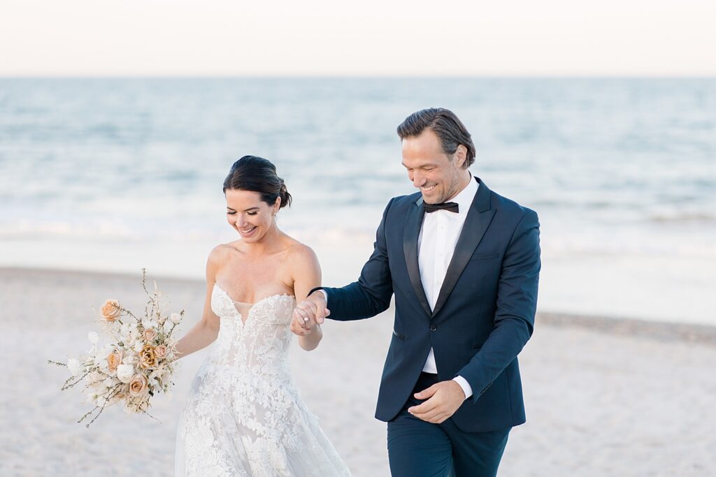 Joyful bride and groom cheering as they celebrate their marriage on the beach at the coastal opulence beach wedding editorial photographed by Brittany Navin Photography