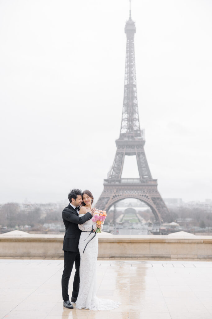 groom hugging bride from behind during wedding portraits in front of the Eiffel Tower during elopement editorial in Paris, France, photographed by Brittany Navin Photography, an Ottawa based destination wedding photographer.