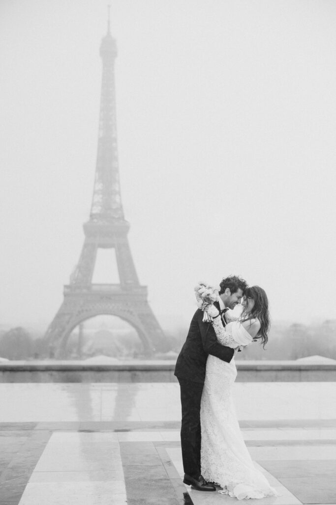 bride and groom share a moment in the rain in front of the eiffel tower during elopement editorial in Paris, France, photographed by Brittany Navin Photography, an Ottawa based destination wedding photographer.
