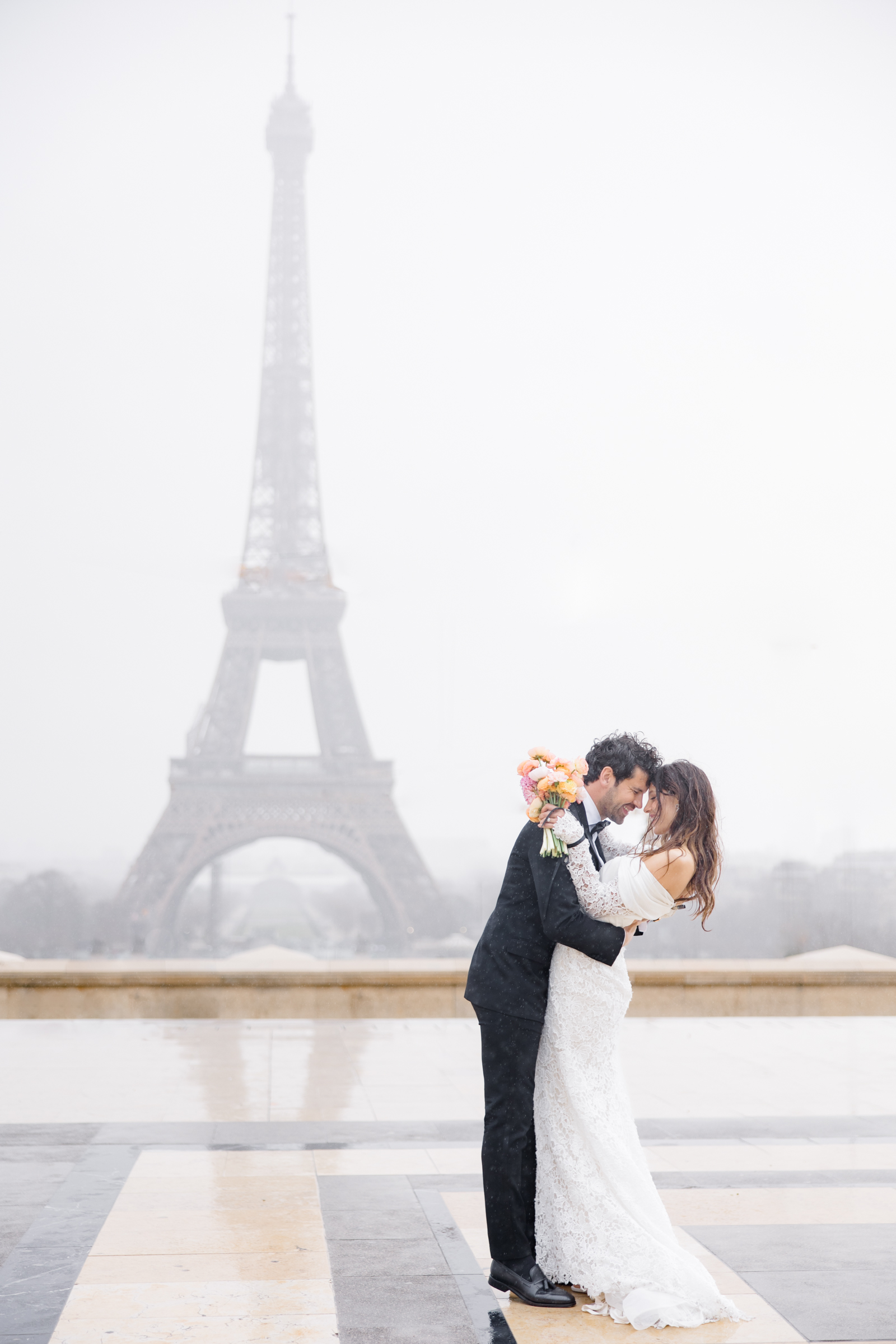 bride and groom in the rain in front of Eiffel Tower during elopement editorial in Paris, France, photographed by Brittany Navin Photography, an Ottawa based destination wedding photographer.