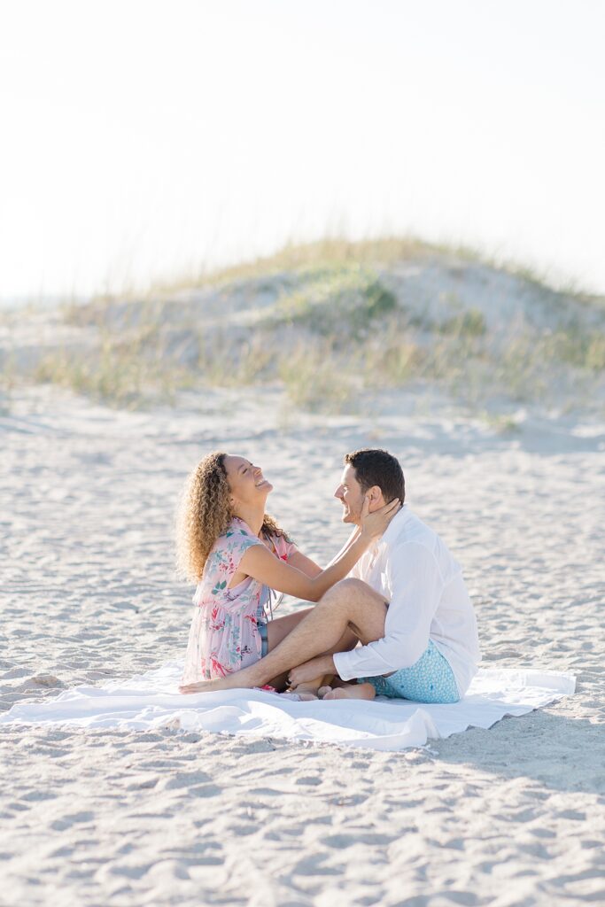 couple laughing while having a picnic on the beach at Amelia Island Honeymoon Session photographed by Brittany Navin Photography 
