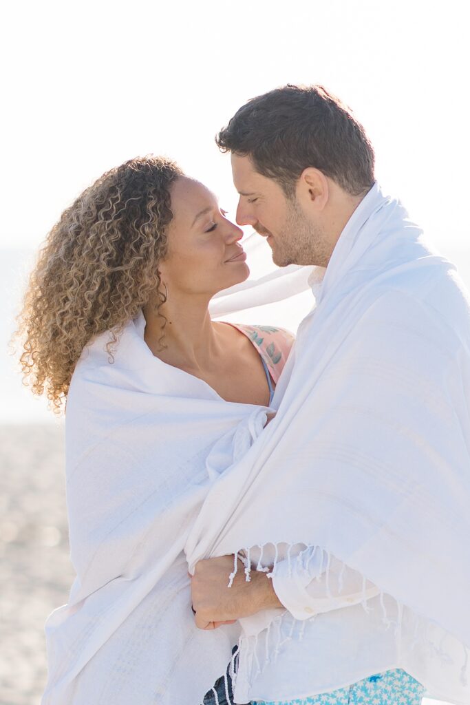 couple cozied up in their beach blanket at Amelia Island Honeymoon Session photographed by Brittany Navin Photography 