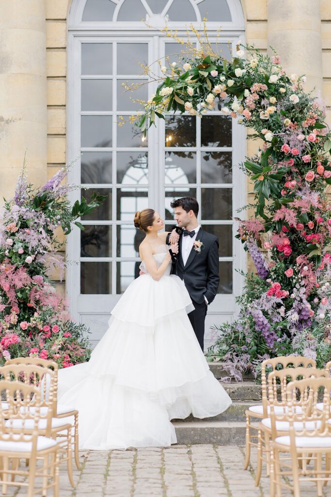 Bride and groom portrait under luscious bloom altar at Chateau De Champlatreux Wedding in Paris, France photographed by destination wedding photographer Brittany Navin Photography