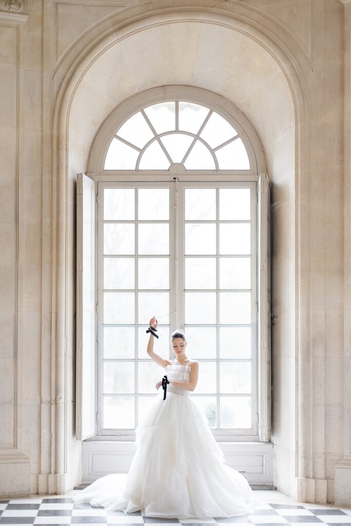 bridal portrait in the stunning arched European window at Chateau De Champlatreux Wedding in Paris, France photographed by destination wedding photographer Brittany Navin Photography