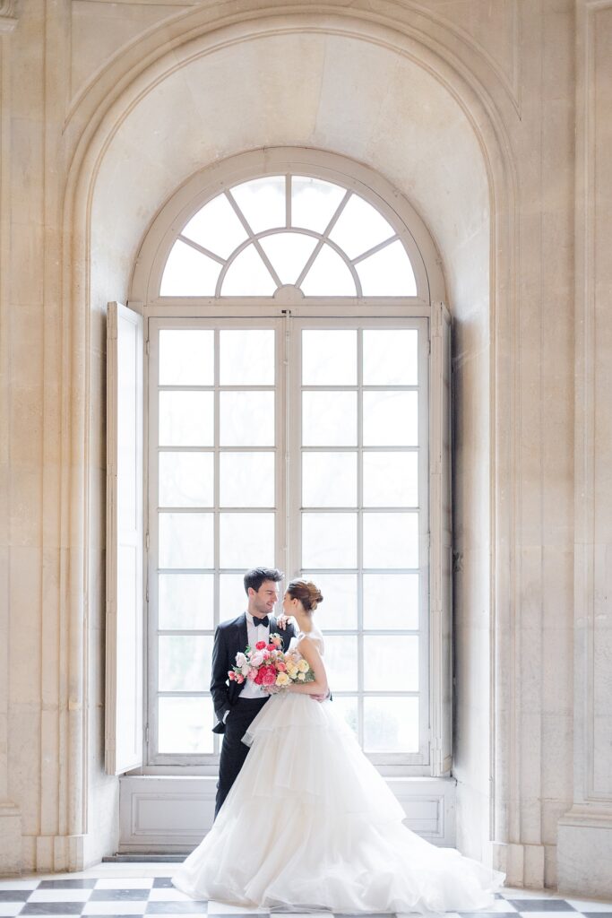 Bride and groom portrait infront of arched european window at Chateau De Champlatreux Wedding in Paris, France photographed by destination wedding photographer Brittany Navin Photography