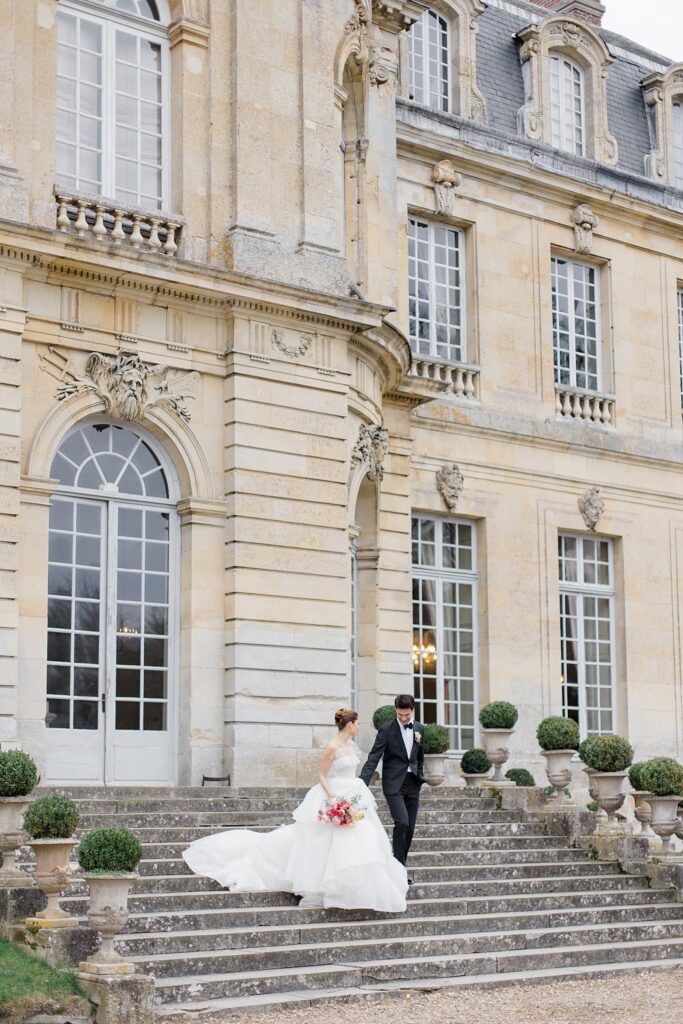 bride and groom walking down the steps at Chateau De Champlatreux Wedding in Paris, France photographed by destination wedding photographer Brittany Navin Photography