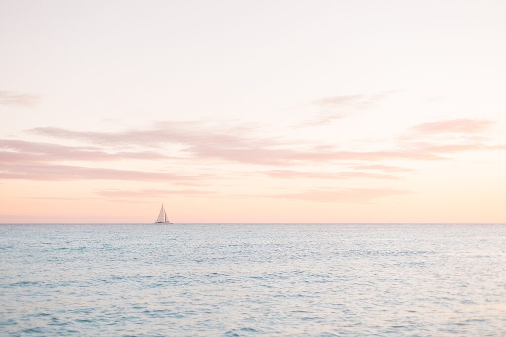 Sail boat off in the distance during sunset in Punta Cana, Dominican Republic photographed by Brittany Navin Photography