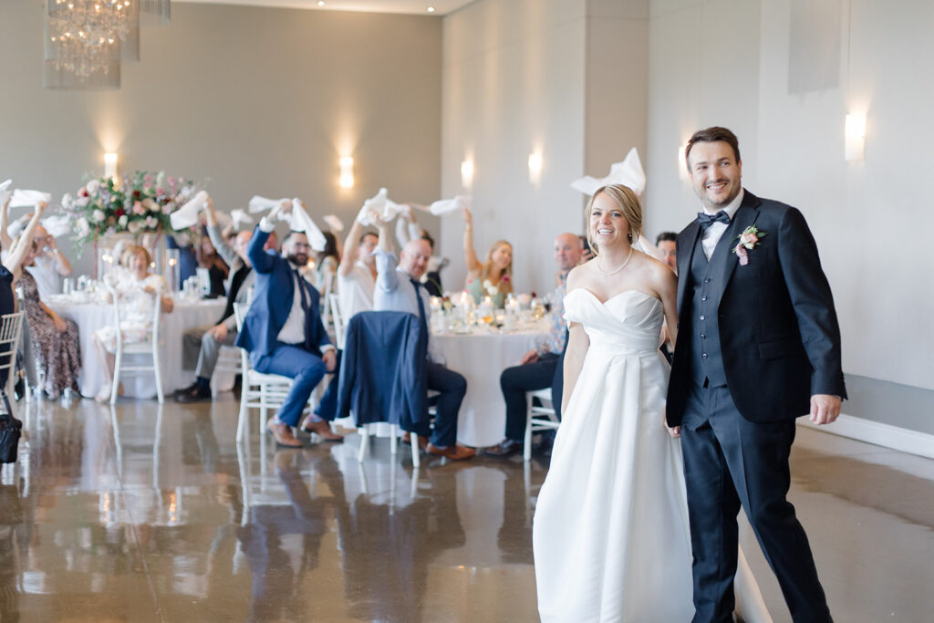 bride and grooms grand entrance as guests swing their napkins around at Le Belvedere Wedding photographed by Brittany Navin Photography, an Ottawa based Destination wedding photographer