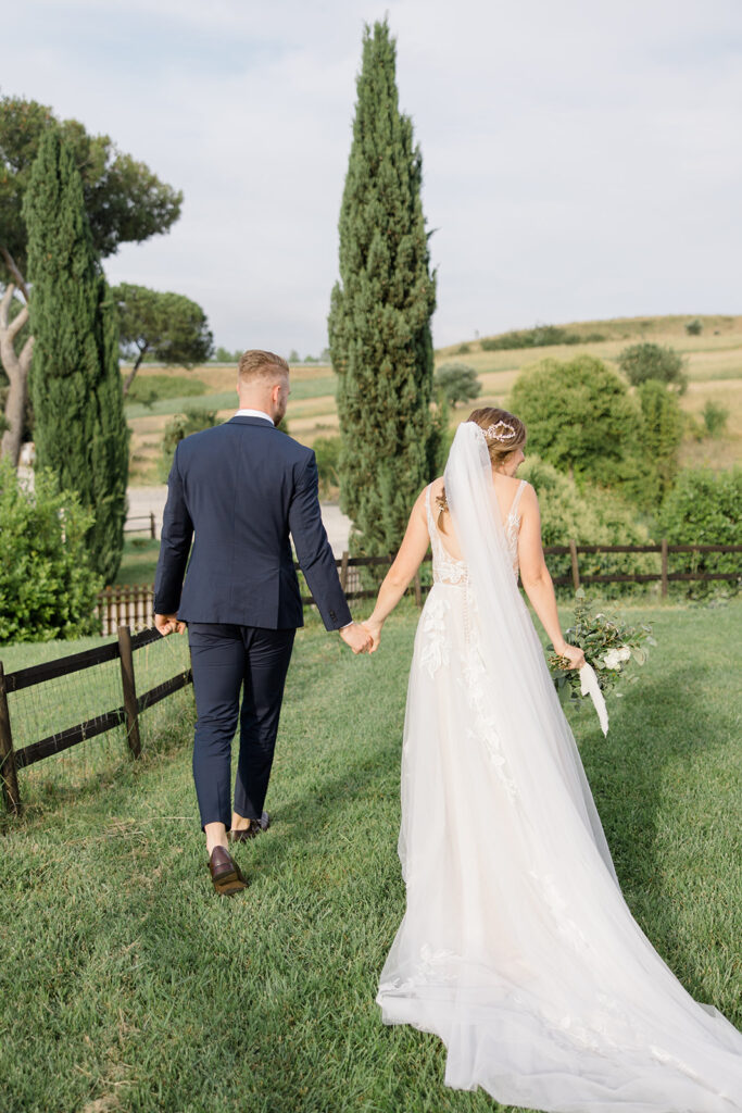bride and groom holding hands as they exit the ceremony at Rome countryside wedding held at Tenuta La Porta Sul Lago photographed by Destination Wedding Photographer Brittany Navin Photography